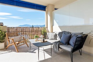 A balcony with a sofa, a chair, a table, and a view of mountains. - Sunny Getaway With Pool in Marbella - Ref M54 (Marbella)