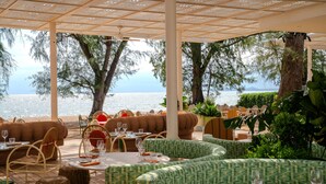 Un restaurante frente al mar con terraza, mesas y sillas.