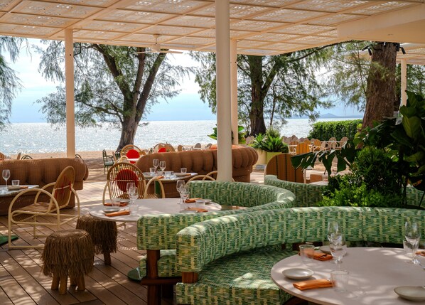 Ein Restaurant am Meer mit Außenbereich, Tischen und Stühlen mit Blick auf den Ozean.