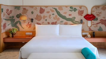 Un lit bien fait, avec du linge de lit blanc, une table de chevet ornée d’une plante et un mur décoré d’un motif floral.