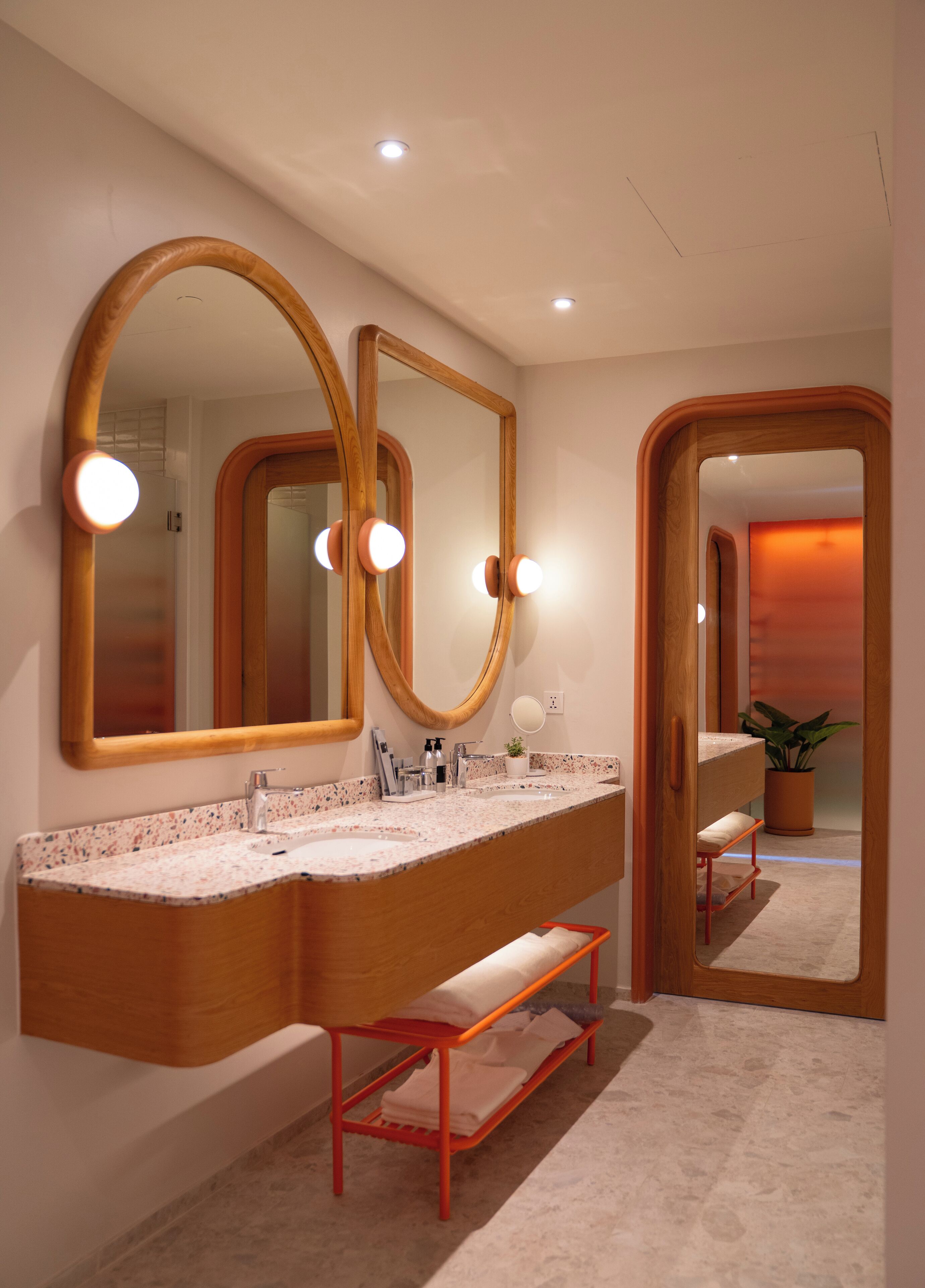 A modern bathroom with two sinks, large mirrors, and a bench.