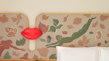Une chambre d’hôtel avec un lit, une table de chevet et un mur orné d’un motif de feuilles.