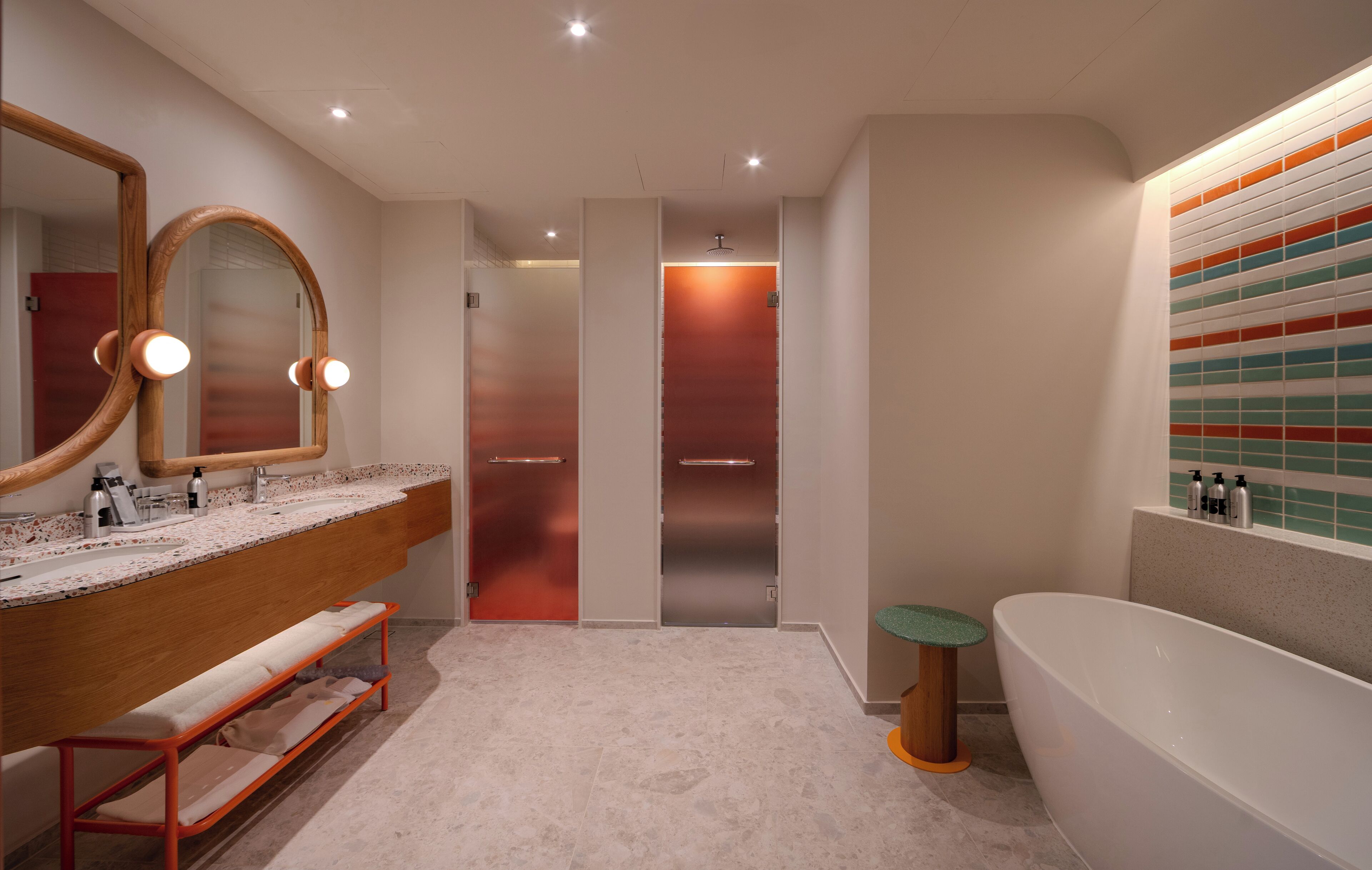 A modern bathroom with a large mirror, a vanity with a countertop, a bench, a bathtub, and a shower area.