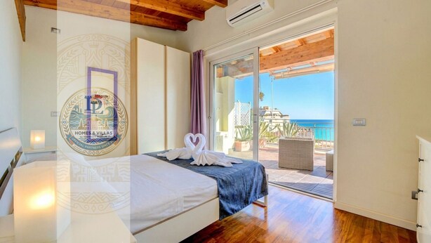 Une chambre avec un lit, une vue sur la mer et un balcon agrémenté de meubles en osier.