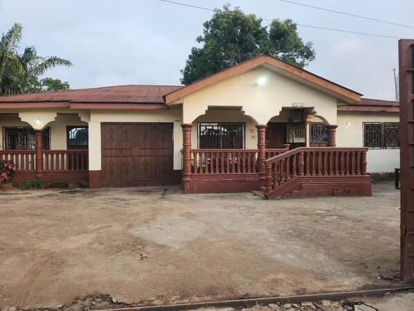 A two-story house with a brown gate, a porch with a railing, and a staircase leading to the entrance. - Hariom Yogi Guest House Yogi Homestay (Lungi)