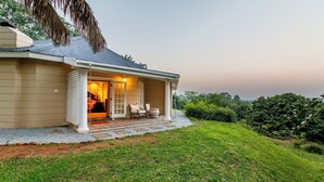 Una casa con porche, cama y vistas al entorno verde.