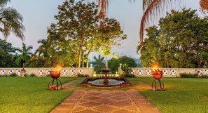 A garden pathway leading to a fountain with two lit fire pits on either side. - Blue Mountain Estate (Mbombela)
