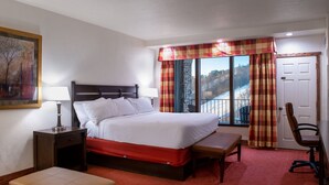 A hotel room with a bed, bedside tables, a bench, a chair, and a large window with curtains. - Champion Hotel | Slopeside Stay + Pool & Spa (Champion)