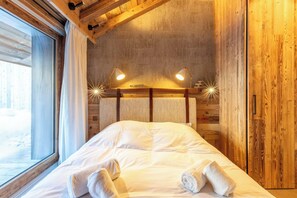 Een gezellig houten vertrek met een bed, twee bedlampen en een raam.