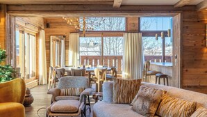 A cozy cabin interior with a wooden interior, a dining area, and a large window offering a view of the outdoors.