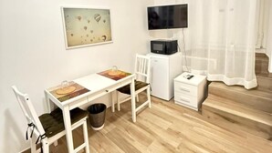 A small, clean room with a wooden floor, a white desk with a chair, a television, and a small white cabinet. - Best Bnb Alfieri (Florence)