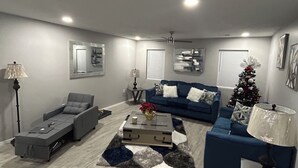 Una sala de estar moderna con un sofá gris, un sofá azul, una mesa de centro y una lámpara de pie.