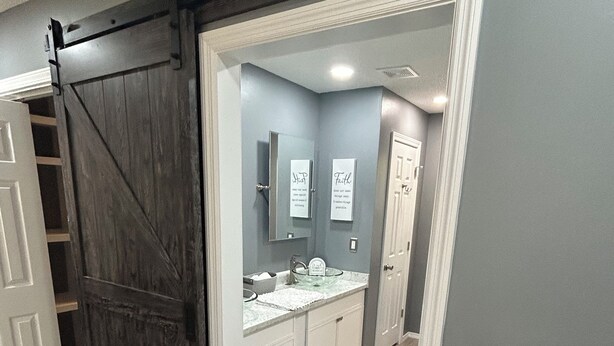Un baño de diseño moderno, con un espejo grande, un lavabo de vidrio y un mueble de tocador blanco.