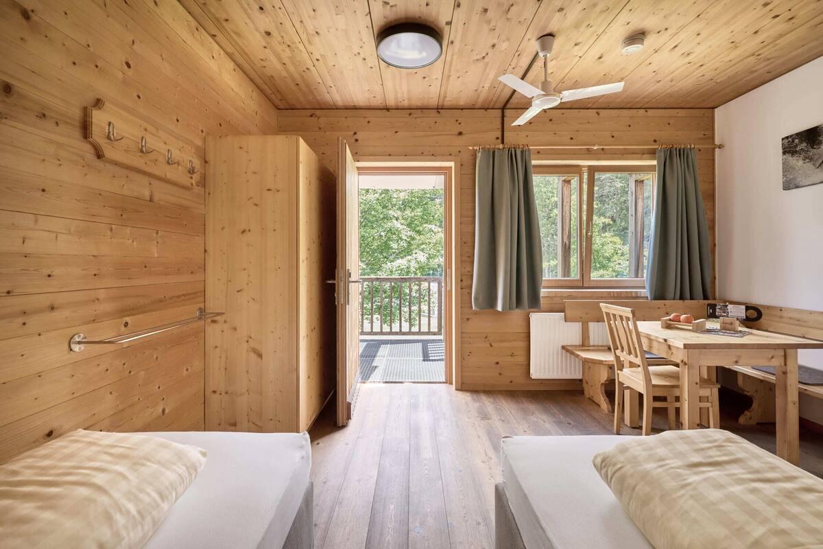 Eine Holz-Blockhütte mit zwei Betten, einem Essbereich und einem Balkon.
