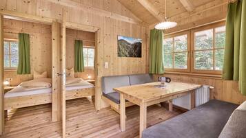 Een houten hutje met een bed, een bank, een tafel en uitzicht op de natuur.