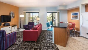 A compact hotel room with a sofa, armchairs, a small dining table, a TV, and a view of the outdoors. - WorldMark Indio, 2 Bedroom/2 Bath Condo for Coachella (Indio)