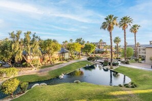 A landscaped area with a pond, palm trees, and buildings in the background. - WorldMark Indio, 2 Bedroom/2 Bath Condo for Coachella (Indio)