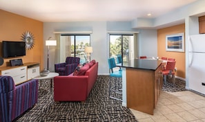 A compact hotel room with a sofa, armchairs, a small dining table, a TV, and a view of the outdoors. - WorldMark Indio, 2 Bedroom/2 Bath Condo for Coachella (Indio)