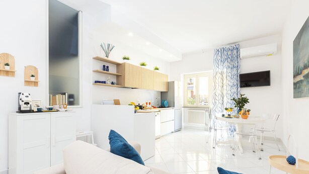 A modern living space with a kitchen, dining area, and a sofa with blue cushions. - Marescala vacation - Doria Home, spacious apartment in Sorrento town. (Sorrento)