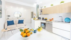 A modern kitchen with white cabinets, a central island, and a dining area with a sofa and coffee table. - Marescala vacation - Doria Home, spacious apartment in Sorrento town. (Sorrento)
