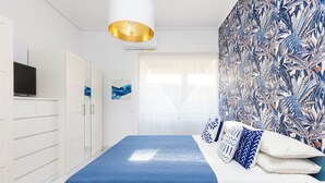 A bedroom with a bed, white wardrobe, and a wall with a tropical leaf pattern. - Marescala vacation - Doria Home, spacious apartment in Sorrento town. (Sorrento)