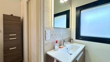 Un baño moderno con un espejo grande, lavamanos dobles y un mueble con cajones.