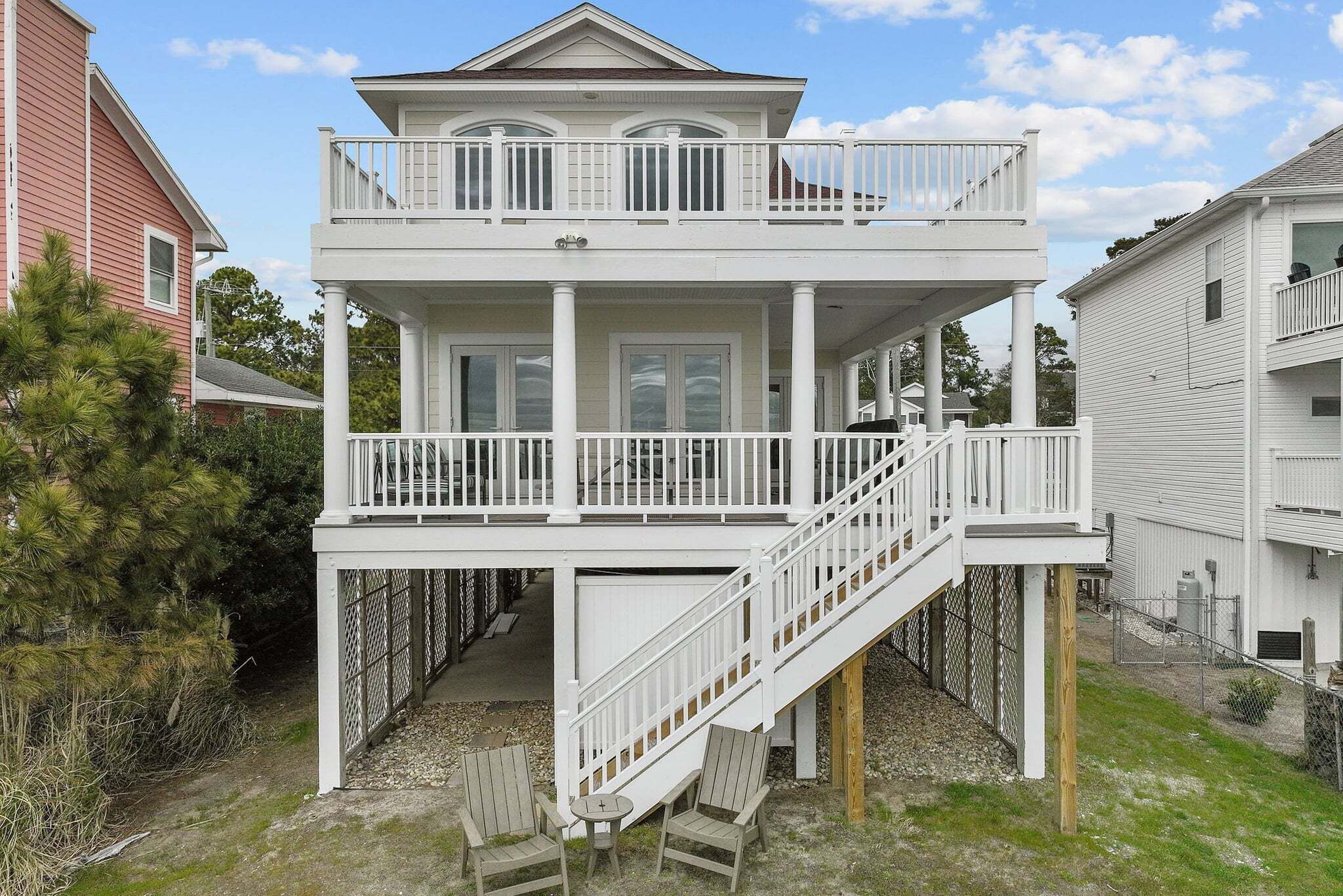 A two-story house with a balcony, a staircase, and a small outdoor seating area.