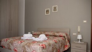 A neatly made bed with floral bedding, a bedside table with a lamp, and two framed pictures on the wall. - Apartment in the heart of Val di Sangro, between Costa dei Trabocchi and Majella. (Piazzano-piana La Fara)