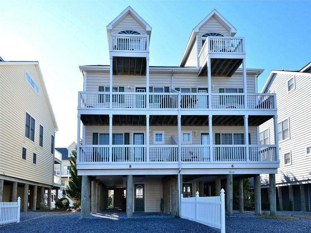 A multi-story building with balconies, a covered entrance, and a gravel driveway.