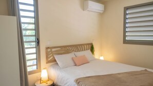 Een slaapkamer met een bed, nachtlampjes, een raam met zonwering en een airconditioning.