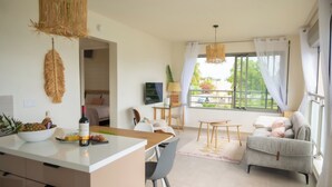 Een moderne woonkamer met een bank, een eethoek en een groot raam met gordijnen.