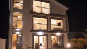 Een modern gebouw met twee verdiepingen, meerdere ramen en een goed verlichte ingang.