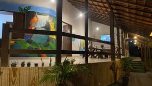 A covered outdoor area with a mural, wooden benches, and potted plants. - Pousada Muretá  (Santarém)