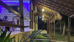 A covered outdoor area with a wooden ceiling, a brick wall, and a thatched roof structure. There are potted plants and a staircase leading to a higher level. - Pousada Muretá  (Santarém)