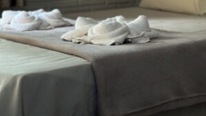 A neatly made bed with a grey bedspread and white towels. - Pousada Muretá  (Santarém)