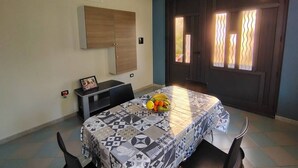 Un coin repas avec une table dressée pour deux personnes, un meuble de rangement au-dessus et une porte dotée de panneaux de verre décoratifs.