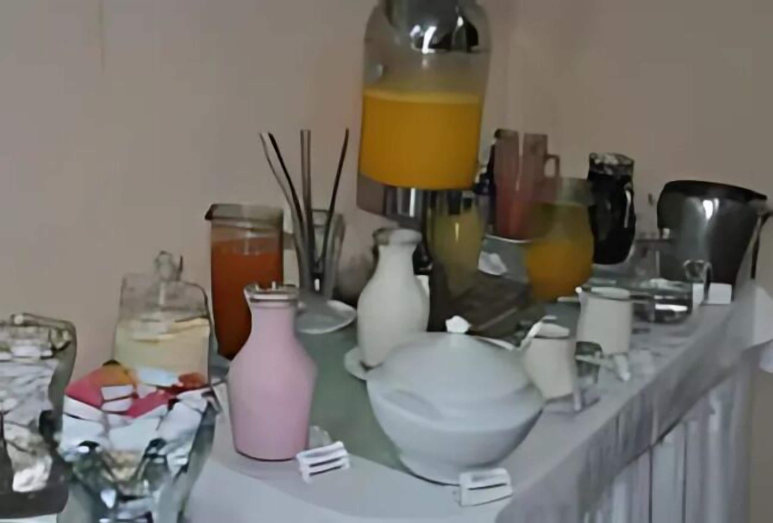 Eine Küchenarbeitsplatte mit verschiedenen Gegenständen, darunter ein Mixer, Gläser, eine rosa Vase und Küchenutensilien.