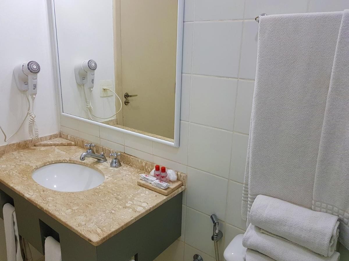A bathroom with a sink, mirror, towel rack, and a towel.