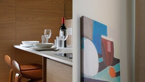 A dining area with a table set for two, a wine bottle, and a painting on the wall. - TBS 304 - Charming studio in Paris (Paris)
