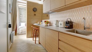 A modern kitchen with wooden cabinets, a built-in oven, and a large island with stools. - TBS 304 - Charming studio in Paris (Paris)