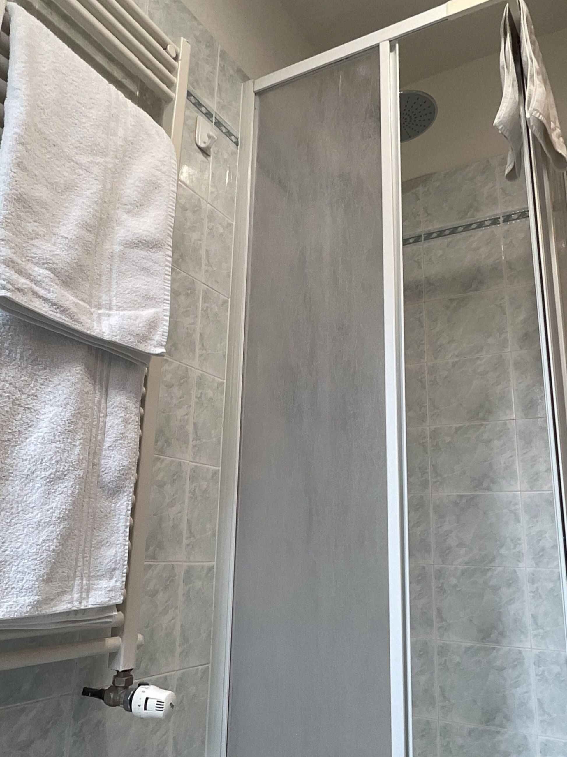 A bathroom with a shower, tiled walls, and a towel rack.