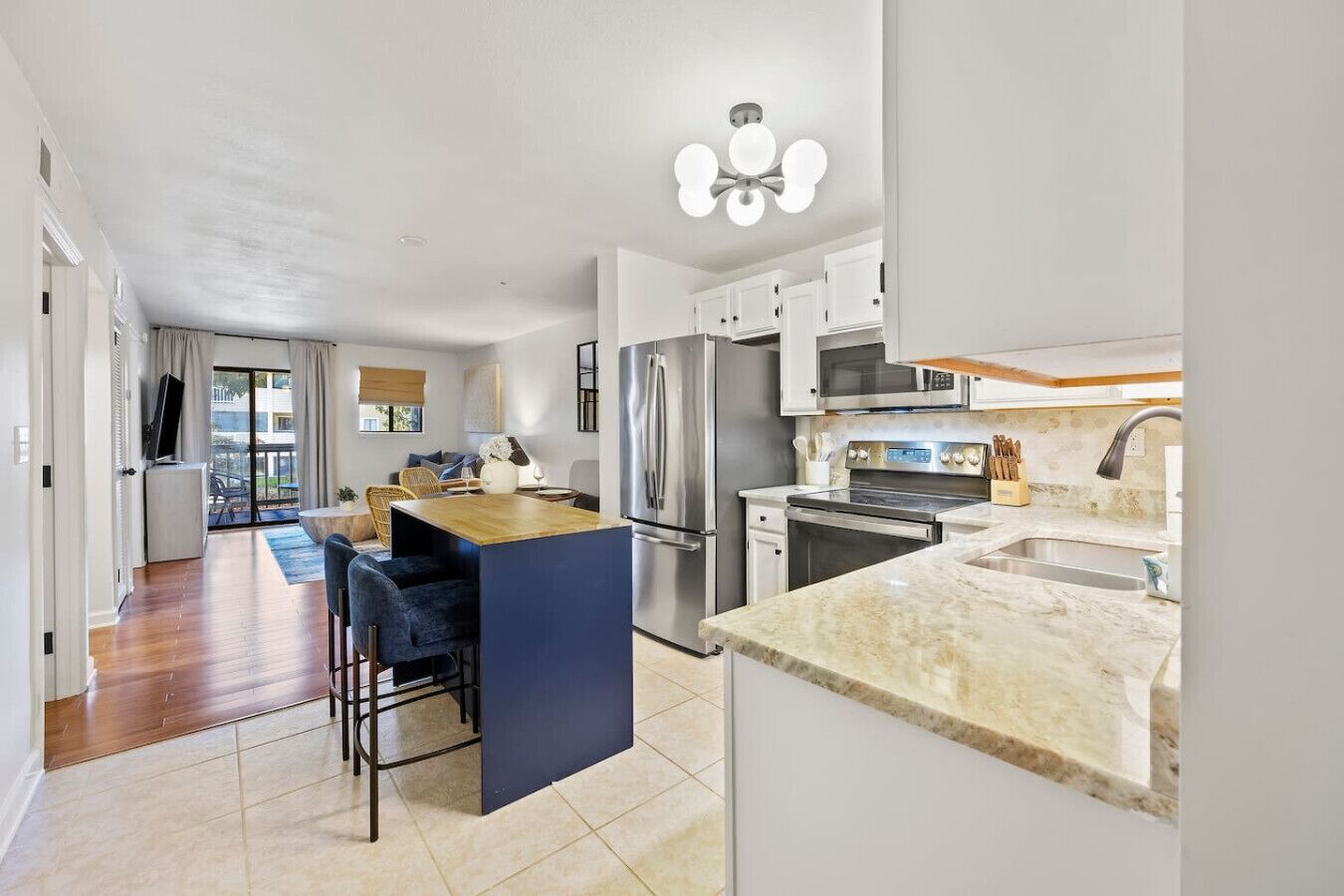 A modern kitchen with a central island, stainless steel appliances, and a large window.