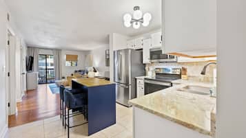 A modern kitchen with a central island, stainless steel appliances, and a large window.