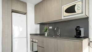 Una cocina moderna con microondas integrado, cafetera y horno pequeño.