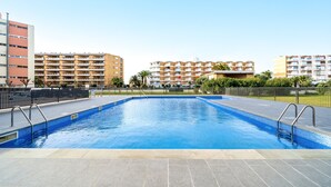 Una piscina con borde de baldosas y barandales de metal, rodeada de edificios de apartamentos.