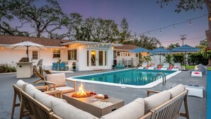 A backyard with a swimming pool, outdoor seating, and string lights.