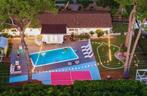 Propiedad residencial con piscina, zona de estar al aire libre y cancha de tenis.