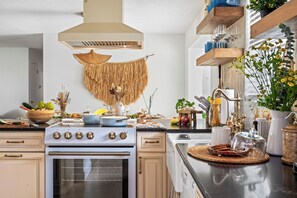 A modern kitchen with a stove, oven, and various kitchen items on the counter.