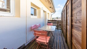 A covered outdoor patio with a table and chairs, wooden walls, and a window.
