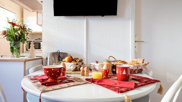 A dining table with a white tablecloth, red napkins, and various breakfast items.